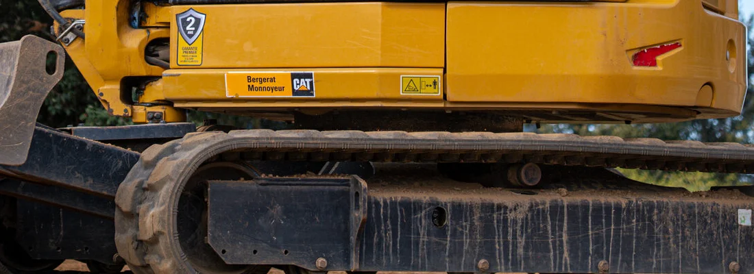 L'étiquette « Bergerat Monnoyeur » et le logo Cat sur le châssis jaune d'une machine, au-dessus de la chenille.