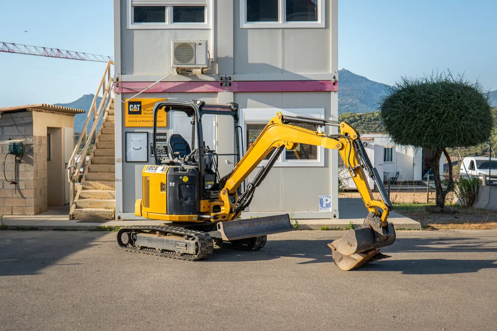 Mini-pelle Caterpillar 2,7 tonnes du parc Locamat, de profil, godet posé au sol