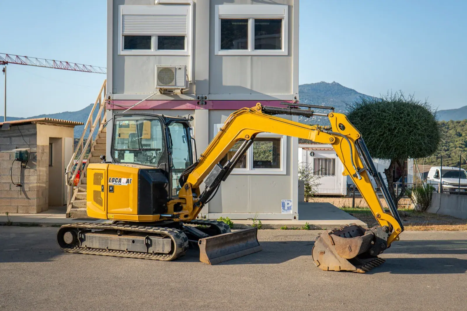 Mini-pelle 5 tonnes à cabine fermée, devant l'agence Locamat à Propriano.